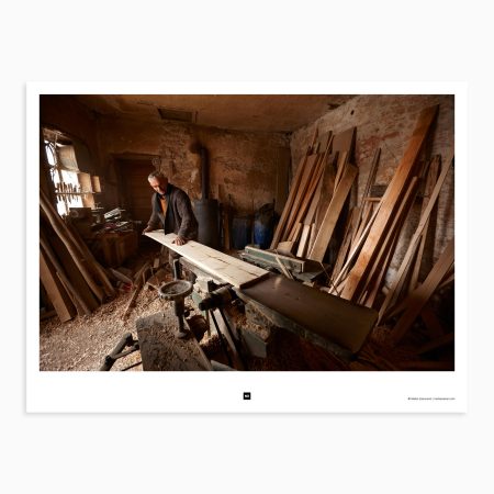 The old carpenter works diligently in his workshop, measuring and cutting the wood with care. His face is stoic, but there is a hint of sadness in his eyes. He is making a coffin for his recently deceased friend, a task that he takes very seriously. Crna Bara, Serbia, 2012.
